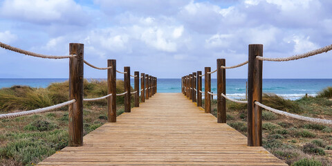 View of the sea and dunes with wooden jetty in the middle in Mallorca