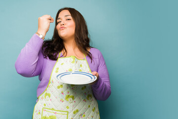Happy fat woman cooking and eating delicious food