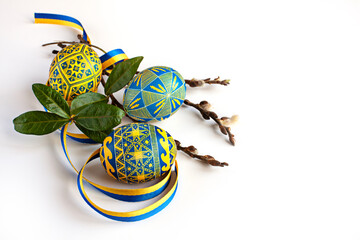 Traditional Ukrainian Easter eggs in national colors, twigs of willow and periwinkle and a yellow-blue ribbon on a white background