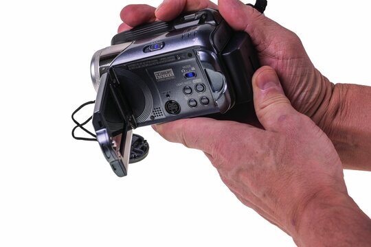 Close-up view of man's hands holding JVC video camera isolated on white background. Sweden 