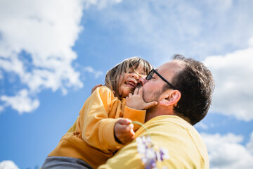 Fototapeta premium low angle view of Father kissing small laughing daughter
