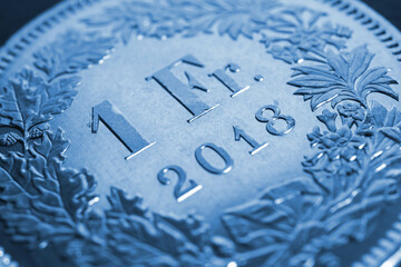 1 Swiss Franc coin close-up. Blue background or wallpaper about economy, business or banking. Money...