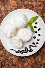 Eating of fresh handmade soft Italian cheese from Puglia, white balls of burrata or burratina cheese made from mozzarella and cream filling served with balsamico cream