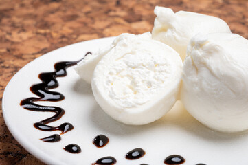 Eating of fresh handmade soft Italian cheese from Puglia, white balls of burrata or burratina cheese made from mozzarella and cream filling served with balsamico cream