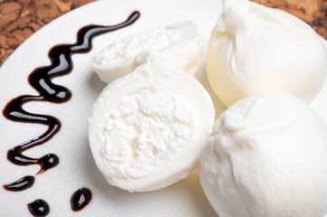 Eating of fresh handmade soft Italian cheese from Puglia, white balls of burrata or burratina cheese made from mozzarella and cream filling served with balsamico cream