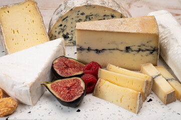 Cheese collection, marble board with French cheeses brie, tomme, matured goat cheese, morbier  served with fresh raspberries and figs