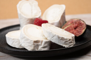 French organic matured white goat cheese with white rind close up served with fresh raspberries and figs
