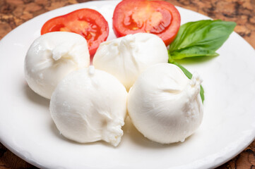 Eating of fresh handmade soft Italian cheese from Puglia, white balls of burrata or burratina...