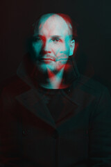 Lifestyle concept. Man with black coat studio portrait. Model with beard looking at camera with serious look. Red and blue color split effect style. 3D glitch virtual reality effect