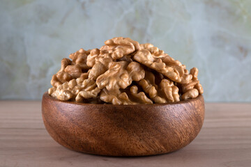 Bowl full of peeled walnuts on a wooden background