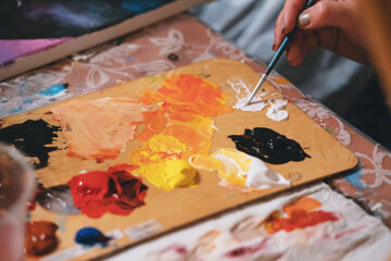 Close-up of painter combine colours on palette. Creamy oil paints on surface. Painter equipment for work. Masterpiece idea and creativity flow.Selective focus
