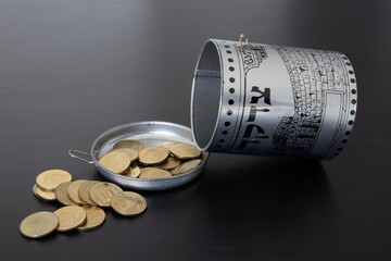 a charity box with coins. Hebrew text [Tzedakah] transltion - Charity.
