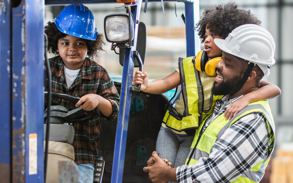 Father Wearing Safety Hard Hat, Teaching Children To Drive Tractor In Factory To Support His Work As Worker, Playing, Smiling, Laughing With Happiness, Love. Industry, Education Concept.