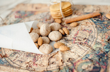 Almond biscuits amaretti. Almonds, gingerbread cookies and a cinnamon stick lie on an old map