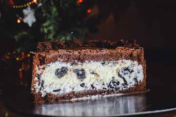 Cut chocolate cake with baked cheesecake and cream, oreo cookies. Side view. Close up