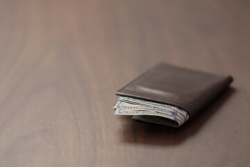 Full grain leather wallet with us dollars on walnut table