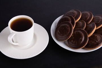 photo of a chocolate-covered cookie and a coffee cup with coffee
