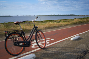 Fototapeta na wymiar Landscape of Grevelinger sea in Holland. Ladies bike on a bike path in the depth blur. Holland, Zeeland, Brouwersdam.