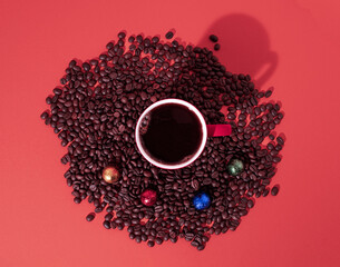 Cup of black coffee, chocolate bars and coffee beans on red background