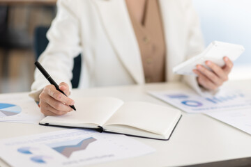 Asian Business woman using calculator and laptop for doing math finance on an office desk, tax, report, accounting, statistics, and analytical research concept
