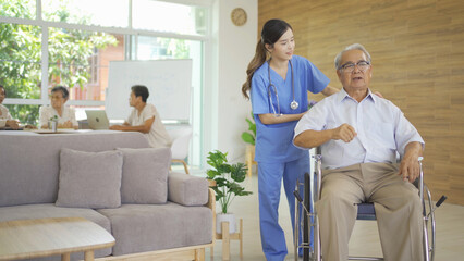 Fototapeta premium An Asian nurse talking to a group of old elderly patient or pensioner people smiling, relaxing, having fun together in nursing home. Senior lifestyle activity recreation. Retirement. Health care