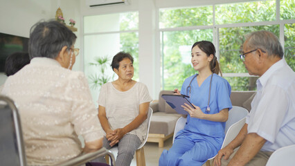 Obraz premium An Asian nurse talking to a group of old elderly patient or pensioner people smiling, relaxing, having fun together in nursing home. Senior lifestyle activity recreation. Retirement. Health care