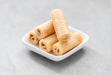 Mini waffle rolls on a plate. Light grey background