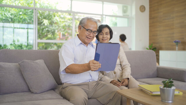 Portrait of happy smiling Asian old couple senior elderly patient using technology tablet device, woman person in hospital in medical healthcare concept. People lifestyle. Family wife and husband