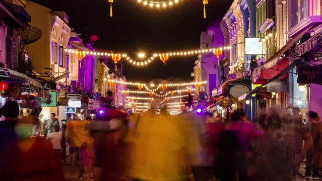 timelapse landscape night view with light illumination on the colonial architecture building with crowded people in Phuket Festival 2023 night time