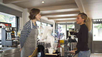 Portrait of woman barista people in apron collecting an order at the counter, coffee shop cafe...
