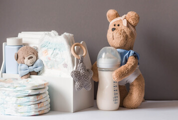 Wooden toys, a bear in a bow tie, a stack of diapers, a bottle and baby supplies on the changing...