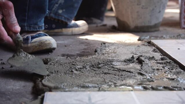 A tiler applies adhesive to the floor to install ceramic tiles. Laying tiles at a construction site. install floor tiles.