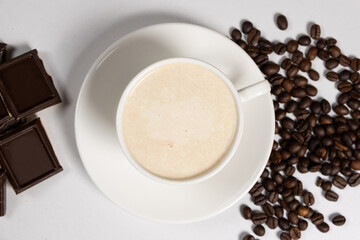 Coffee with milk cream, cappuccino in a saucer cup and chocolate on a white background