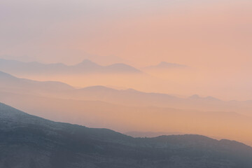 A magical dawn over the Caucasus Mountains with pink layers of mountain ranges and an orange sky