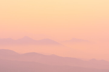 A magical dawn over the Caucasus Mountains with pink layers of mountain ranges and an orange sky
