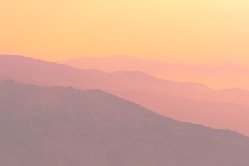 A magical dawn over the Caucasus Mountains with pink layers of mountain ranges and an orange sky