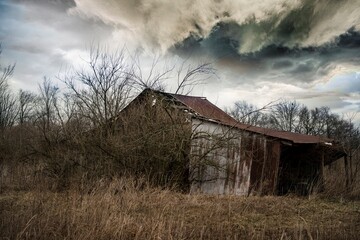 Fototapeta na wymiar storm clouds over an old barn in a farm field