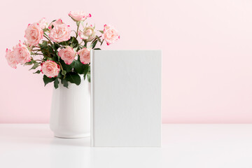 White book cover mock up, vase with pink flowersroses on pink wall background. Front view. Place for text, copy space, mockup