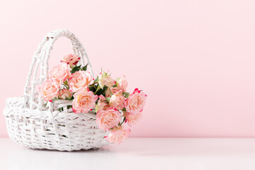 Fototapeta na wymiar Bouquet beautiful flowers pink roses in white wicker basket on pastel pink background table. Birthday, Wedding, Mother's Day, Valentine's day, Women's Day. Front view