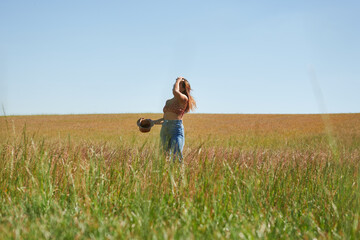 young Hispanic woman wearing a hat posing on a wheat field on a sunny day