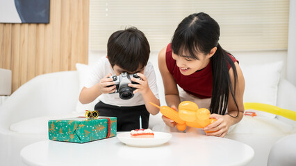 Asian young mother  teaching her son to take a photo of cake. Happy birthday kid how to record and...