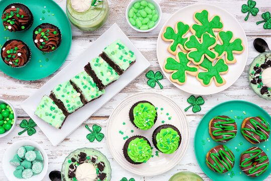 St Patricks Day theme desserts. Table scene over a white wood background. Shamrock cookies, green cupcakes, brownies, donuts and sweets. Top view.