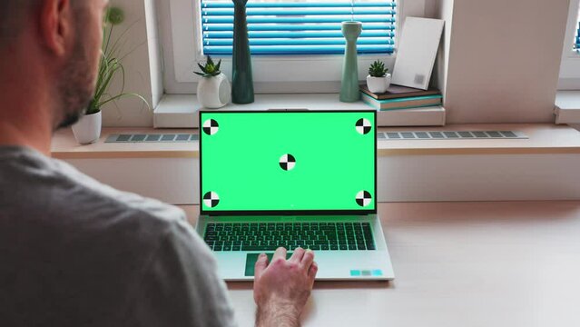 Videocall. Rear view of man watching at green screen of laptop. Copy space and mock up with chromakey. Concept of business and remote online work.