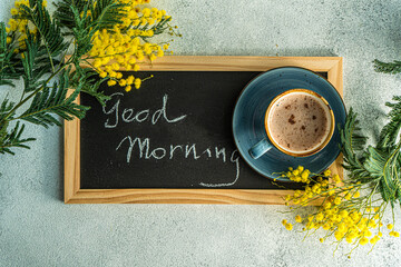 Coffee and mimosa flowers with Good Morning on chalkboard