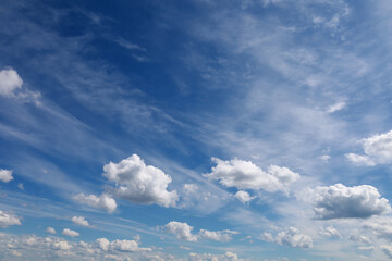 Blue sky with clouds. Spring or summer background. 
White clouds on the blue sky have a complex pattern.
