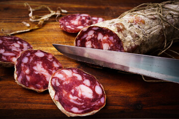 Piacenza salami cut on the wooden cutting board