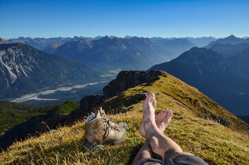 Beine und Wanderstiefel bei Rast mit Panorama auf Gipfel in den Alpen