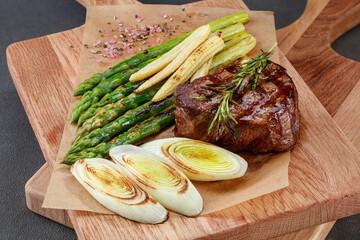 Medium rare fillet mignon steak with fried leek, asparagus and corn on a wooden board. Selective...