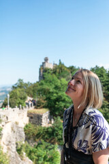 Young beautiful woman smiles against the backdrop of the Guaita Fortress, San Marino, Italy
