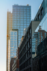 Naklejka premium Modern city building architecture apartments. Low angle view of skyscrapers. Looking up perspective. Bottom view of modern skyscrapers in a business district. Cityscape at daylight. 